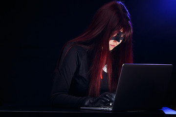 Image showing Young brunette thief with laptop