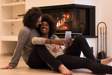 Image showing multiethnic couple using tablet computer on the floor