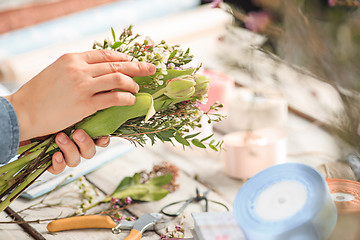 Image showing Florist at work: the female hands of woman making fashion modern bouquet of different flowers