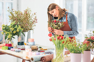 Image showing Florist at work: the female hands of woman making fashion modern bouquet of different flowers