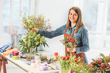 Image showing Florist at work: the young girl making fashion modern bouquet of different flowers