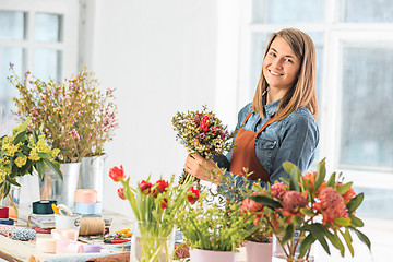 Image showing Florist at work: the young girl making fashion modern bouquet of different flowers