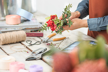 Image showing Florist at work: the female hands of woman making fashion modern bouquet of different flowers