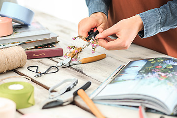 Image showing Florist at work: the female hands of woman making fashion modern bouquet of different flowers