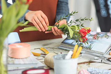 Image showing Florist at work: the female hands of woman making fashion modern bouquet of different flowers