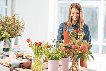 Image showing Florist at work: the female hands of woman making fashion modern bouquet of different flowers