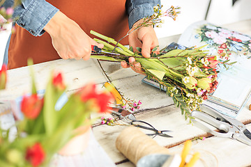 Image showing Florist at work: the female hands of woman making fashion modern bouquet of different flowers