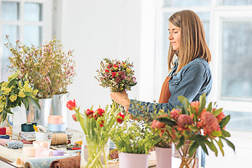 Image showing Florist at work: the young girl making fashion modern bouquet of different flowers