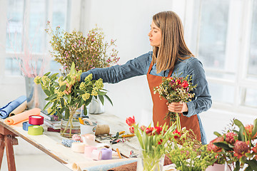 Image showing Florist at work: the young girl making fashion modern bouquet of different flowers