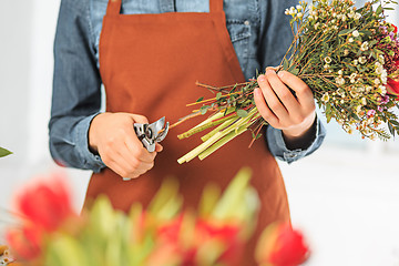 Image showing Florist at work: the female hands of woman making fashion modern bouquet of different flowers