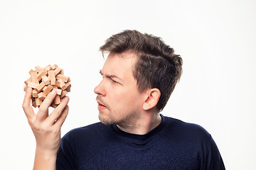 Image showing Attractive 25 year old business man looking confused at wooden puzzle.