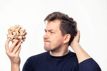 Image showing Attractive 25 year old business man looking confused at wooden puzzle.