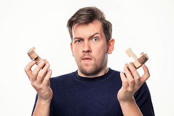 Image showing Attractive 25 year old business man looking confused with wooden puzzle.