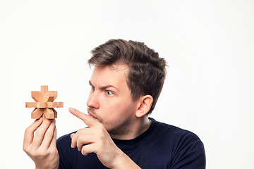 Image showing Attractive 25 year old business man looking confused at wooden puzzle.