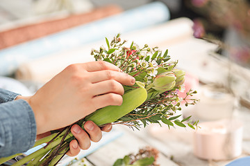 Image showing Florist at work: the female hands of woman making fashion modern bouquet of different flowers