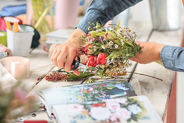 Image showing Florist at work: the female hands of woman making fashion modern bouquet of different flowers