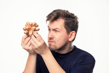 Image showing Attractive 25 year old business man looking confused at wooden puzzle.