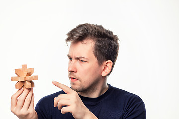 Image showing Attractive 25 year old business man looking confused at wooden puzzle.