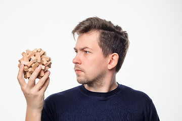 Image showing Attractive 25 year old business man looking confused at wooden puzzle.