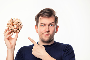 Image showing Attractive 25 year old business man looking confused with wooden puzzle.