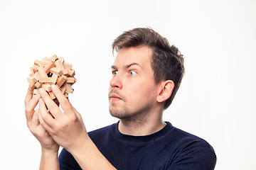 Image showing Attractive 25 year old business man looking confused at wooden puzzle.