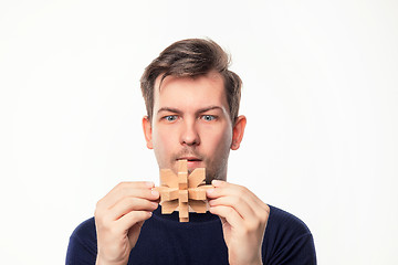 Image showing Attractive 25 year old business man looking confused at wooden puzzle.