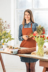 Image showing Florist at work: the young girl making fashion modern bouquet of different flowers