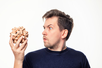 Image showing Attractive 25 year old business man looking confused at wooden puzzle.