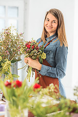 Image showing Florist at work: the young girl making fashion modern bouquet of different flowers