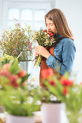 Image showing Florist at work: the young girl making fashion modern bouquet of different flowers