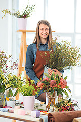 Image showing Florist at work: the young girl making fashion modern bouquet of different flowers