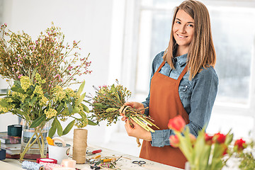 Image showing Florist at work: the young girl making fashion modern bouquet of different flowers