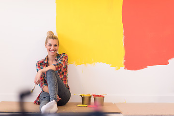 Image showing young female painter sitting on floor