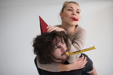 Image showing couple in party hats blowing in whistle