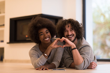 Image showing multiethnic couple showing a heart with their hands on the floor