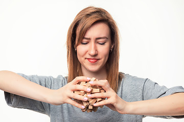 Image showing Attractive 24 year old business woman looking confused with wooden puzzle.