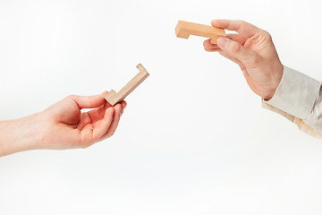 Image showing The toy wooden puzzle in hands solated on white background