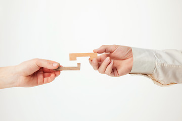 Image showing The toy wooden puzzle in hands solated on white background