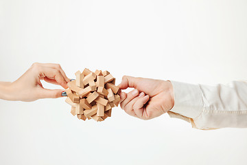 Image showing The toy wooden puzzle in hands isolated on white background