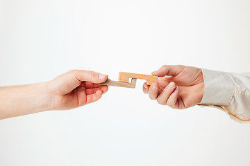 Image showing The toy wooden puzzle in hands solated on white background