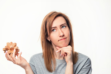 Image showing Attractive 24 year old business woman looking confused with wooden puzzle.