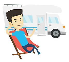 Image showing Man sitting in chair in front of camper van.