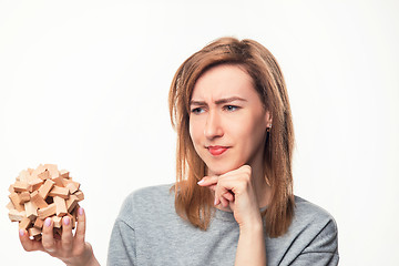 Image showing Attractive 24 year old business woman looking confused with wooden puzzle.