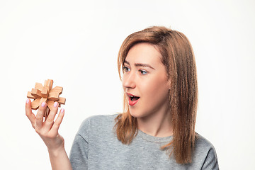 Image showing Attractive 24 year old business woman looking confused with wooden puzzle.