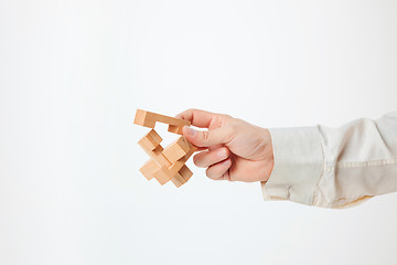 Image showing The toy wooden puzzle in hand isolated on white background