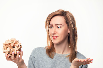 Image showing Attractive 24 year old business woman looking confused with wooden puzzle.