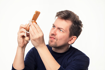 Image showing Attractive 25 year old business man looking confused at wooden puzzle.