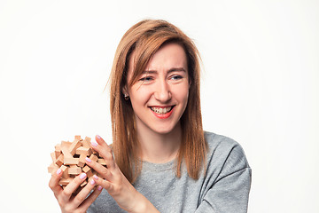 Image showing Attractive 24 year old business woman looking confused with wooden puzzle.