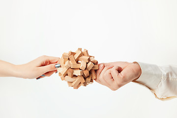 Image showing The toy wooden puzzle in hands isolated on white background