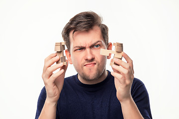 Image showing Attractive 25 year old business man looking confused with wooden puzzle.